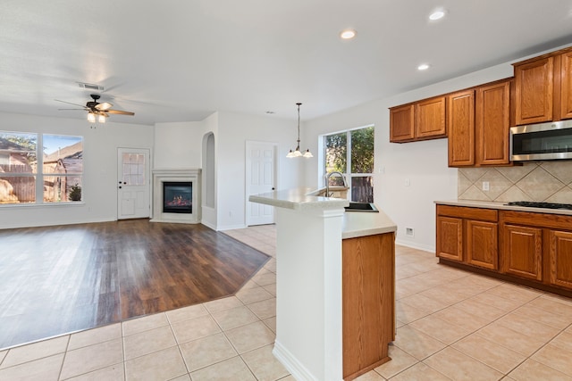 kitchen featuring white gas cooktop, backsplash, sink, hanging light fixtures, and light tile patterned flooring