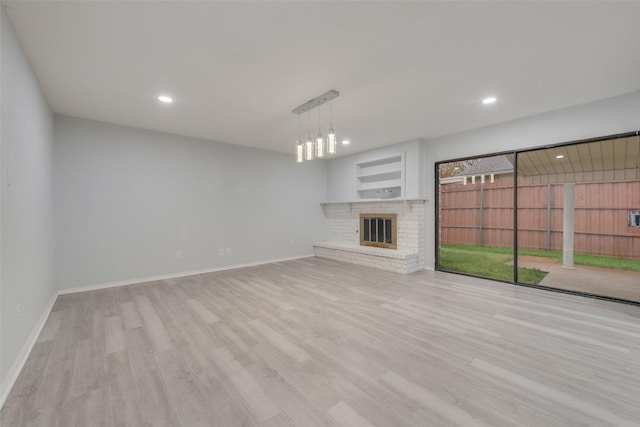 unfurnished living room featuring light hardwood / wood-style flooring and a brick fireplace