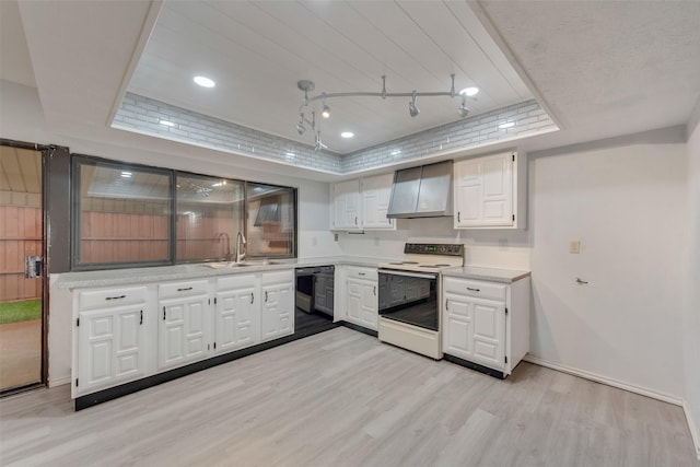 kitchen featuring sink, wall chimney range hood, white electric stove, a tray ceiling, and white cabinets