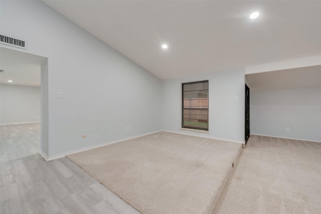 spare room with vaulted ceiling and light wood-type flooring