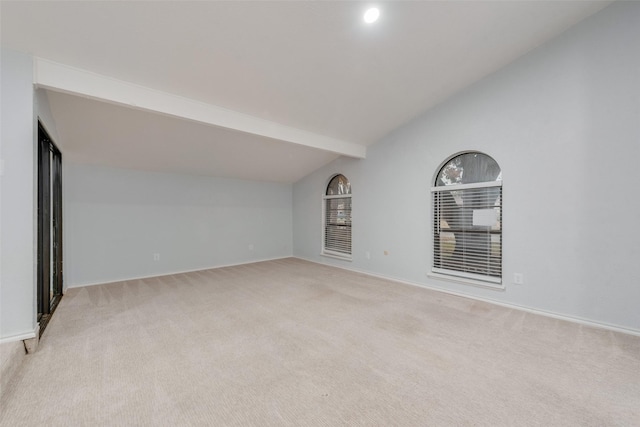 spare room with light carpet and vaulted ceiling with beams