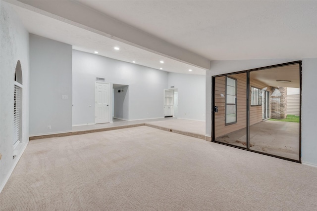 carpeted empty room with beam ceiling