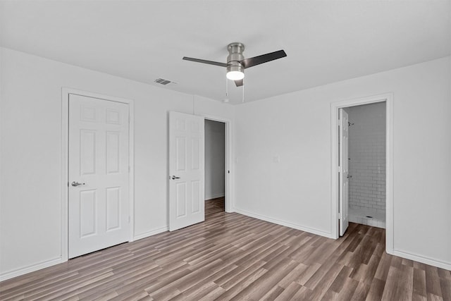 unfurnished bedroom featuring hardwood / wood-style floors, ceiling fan, and ensuite bathroom