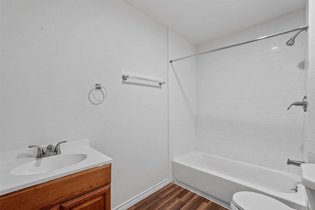 full bathroom with vanity, hardwood / wood-style flooring, tiled shower / bath combo, and toilet