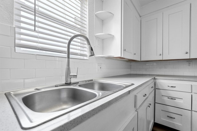 kitchen with backsplash, sink, and white cabinets