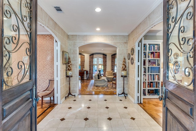 foyer entrance with crown molding, light hardwood / wood-style floors, and tile walls