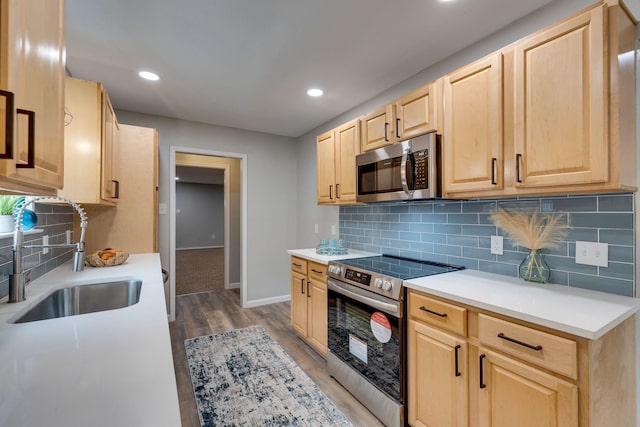 kitchen featuring light brown cabinetry, light wood-type flooring, sink, and appliances with stainless steel finishes