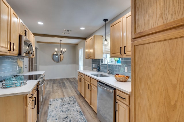 kitchen with decorative light fixtures, sink, stainless steel appliances, and light hardwood / wood-style flooring