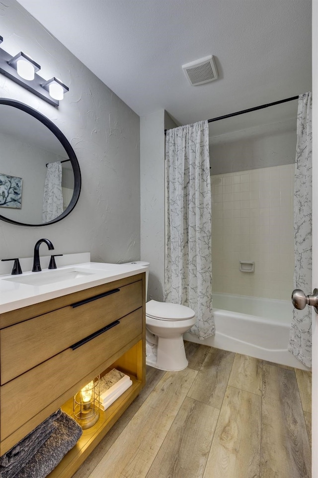 full bathroom with hardwood / wood-style floors, vanity, shower / tub combo, and toilet