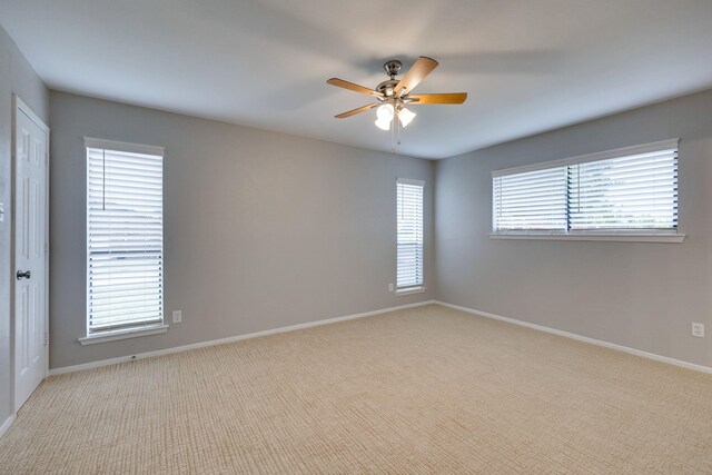 empty room featuring plenty of natural light, ceiling fan, and light colored carpet