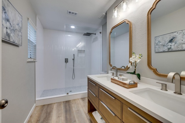 bathroom featuring vanity, wood-type flooring, and tiled shower