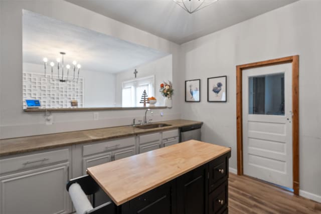 kitchen with an inviting chandelier, dark wood-type flooring, dishwasher, and sink