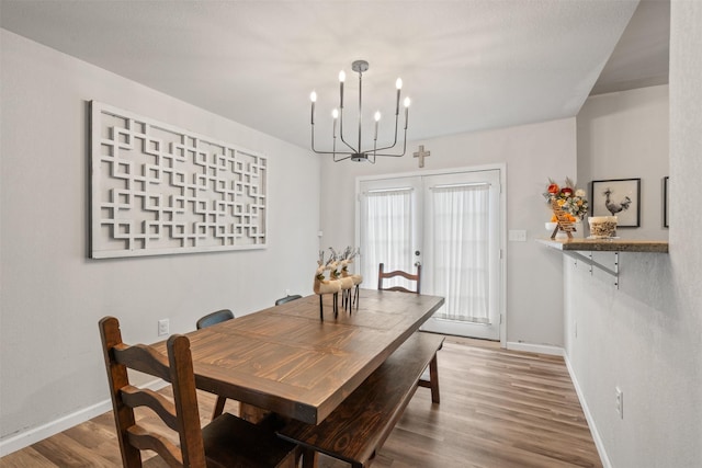 dining room with french doors, wood-type flooring, and a chandelier