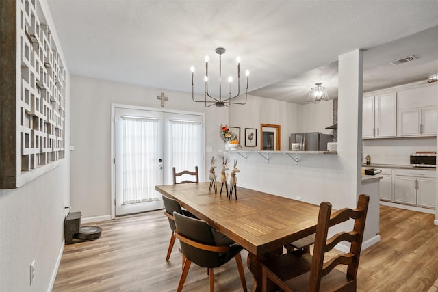 dining area with light hardwood / wood-style floors, french doors, and a chandelier