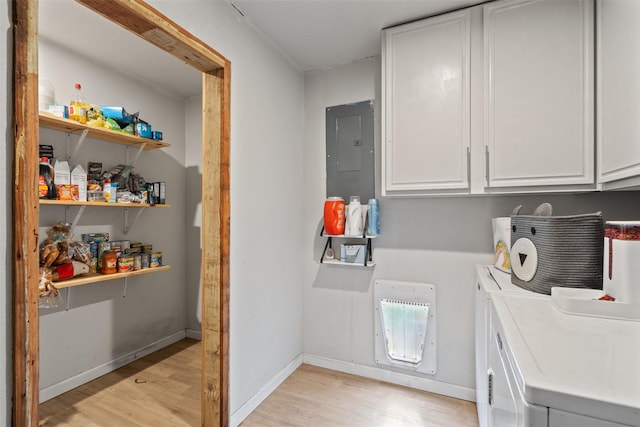 laundry room featuring cabinets, electric panel, washer and clothes dryer, and light hardwood / wood-style flooring