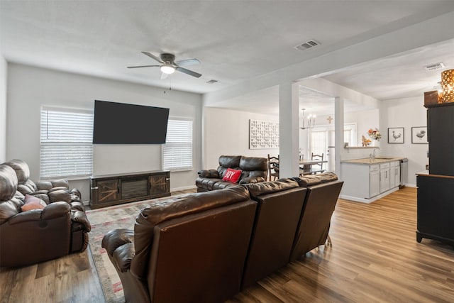 living room featuring sink, ceiling fan with notable chandelier, and light hardwood / wood-style floors