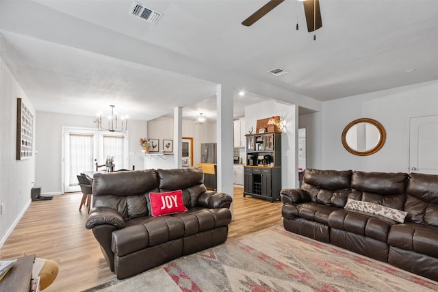 living room with ceiling fan with notable chandelier and light wood-type flooring