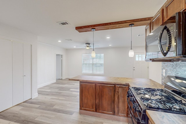 kitchen featuring a wealth of natural light, pendant lighting, light wood-type flooring, and stainless steel range with gas stovetop