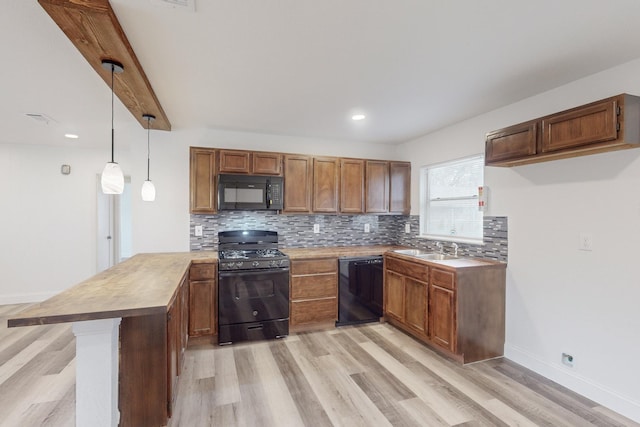 kitchen with black appliances, light hardwood / wood-style floors, and hanging light fixtures