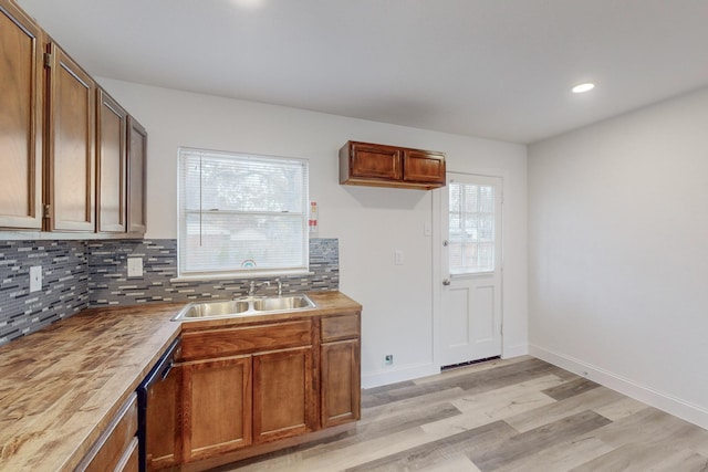 kitchen featuring wood counters, backsplash, sink, stainless steel dishwasher, and light hardwood / wood-style floors