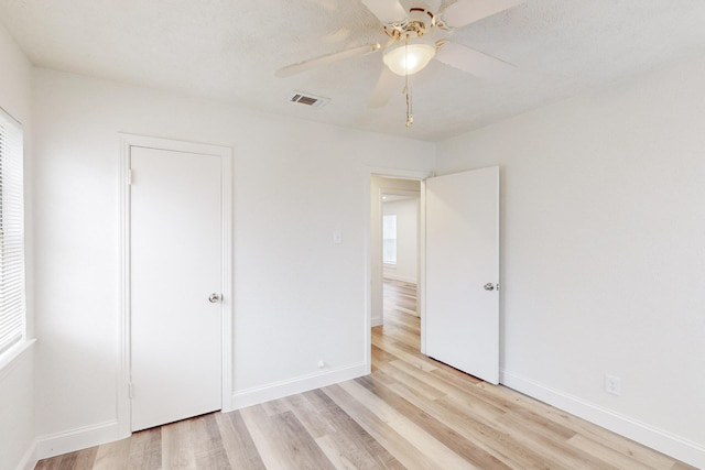 unfurnished bedroom featuring ceiling fan, light hardwood / wood-style floors, and a textured ceiling