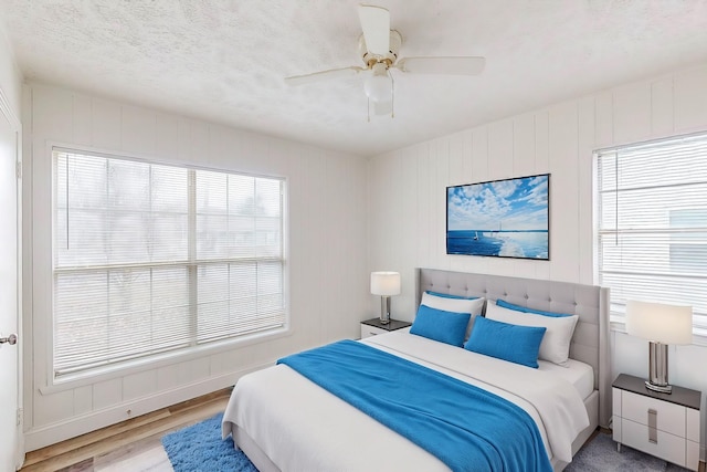 bedroom featuring ceiling fan, light wood-type flooring, and a textured ceiling