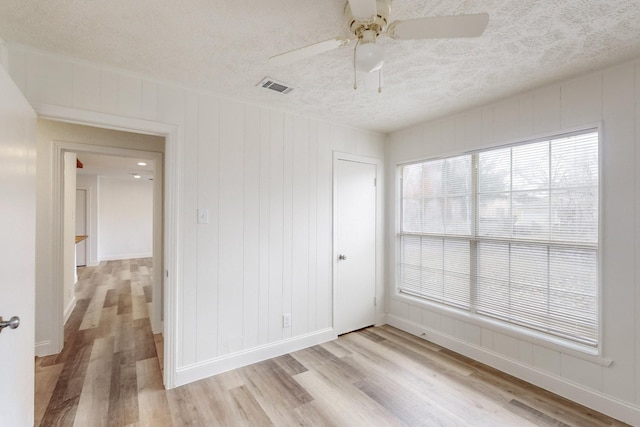 spare room with ceiling fan, light hardwood / wood-style floors, and a textured ceiling