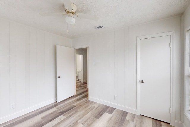 unfurnished room featuring ceiling fan, light hardwood / wood-style floors, and a textured ceiling