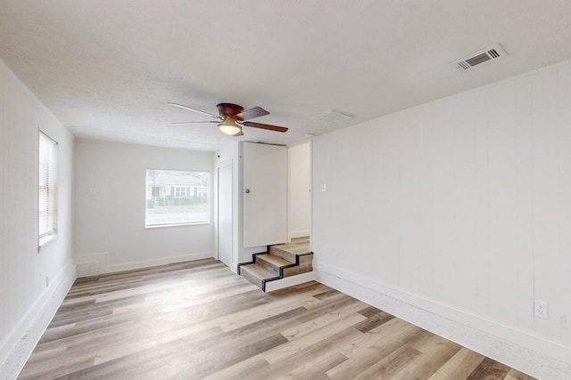 empty room featuring a textured ceiling, light hardwood / wood-style floors, and ceiling fan