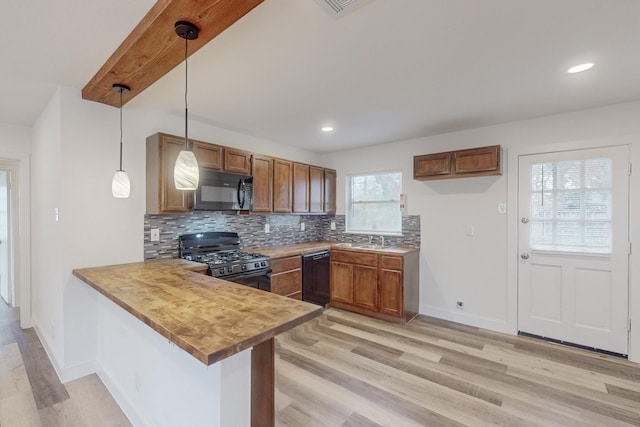 kitchen featuring kitchen peninsula, decorative light fixtures, light hardwood / wood-style floors, and black appliances