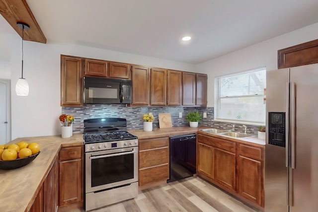 kitchen featuring decorative backsplash, pendant lighting, black appliances, and sink