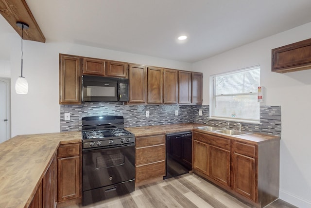 kitchen with pendant lighting, sink, tasteful backsplash, and black appliances