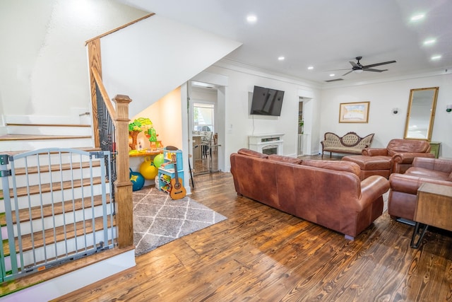 living room featuring crown molding, a fireplace, ceiling fan, and dark hardwood / wood-style floors