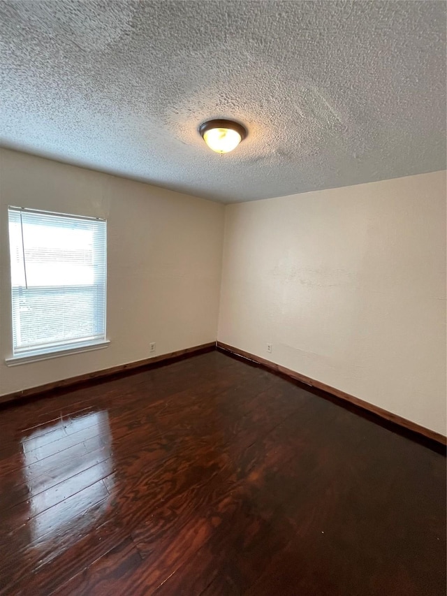 spare room featuring dark wood-type flooring and a textured ceiling