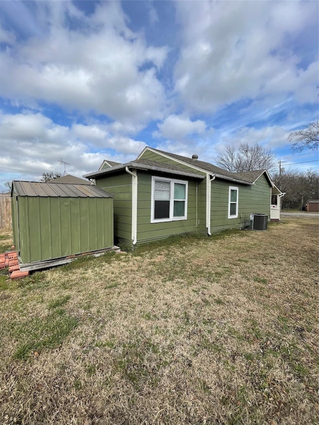 exterior space with central AC, a shed, and a lawn