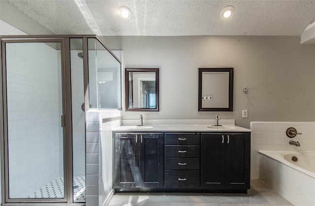 bathroom featuring plus walk in shower, vanity, and a textured ceiling