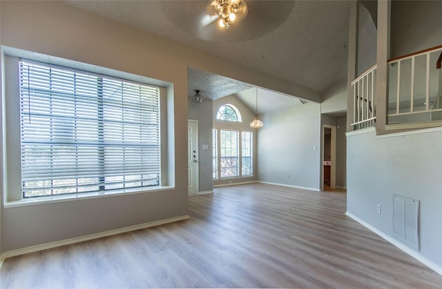 unfurnished living room with wood-type flooring, plenty of natural light, lofted ceiling, and ceiling fan