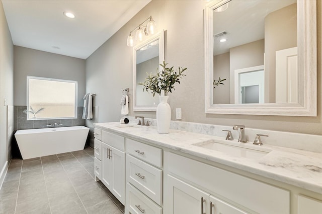 bathroom with tile patterned flooring, a bathtub, and vanity