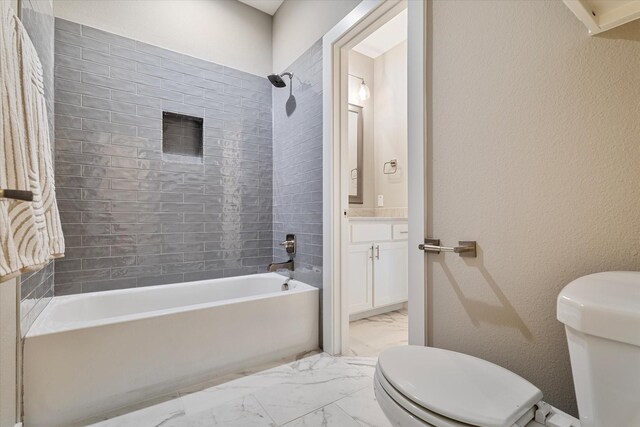 full bathroom featuring tiled shower / bath combo, toilet, and vanity