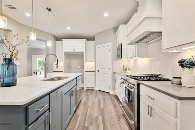 kitchen with stainless steel appliances, white cabinetry, premium range hood, and sink