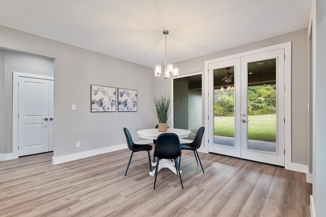 dining space with light wood-type flooring and an inviting chandelier