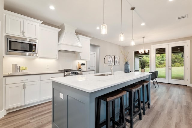 133 Pueblo Dr, Lake Kiowa, TX 76240 - kitchen featuring stainless steel appliances, a sink, custom exhaust hood, light wood-style floors, and a kitchen island with sink