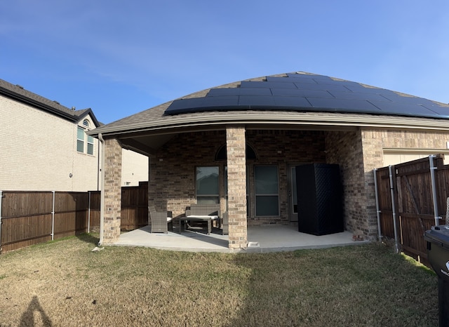 rear view of house with a lawn, solar panels, and a patio