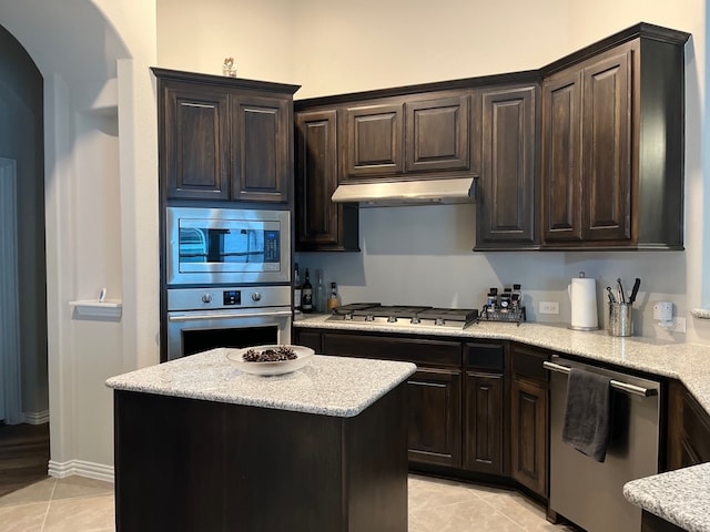 kitchen featuring dark brown cabinets, a kitchen island, light tile patterned flooring, and stainless steel appliances