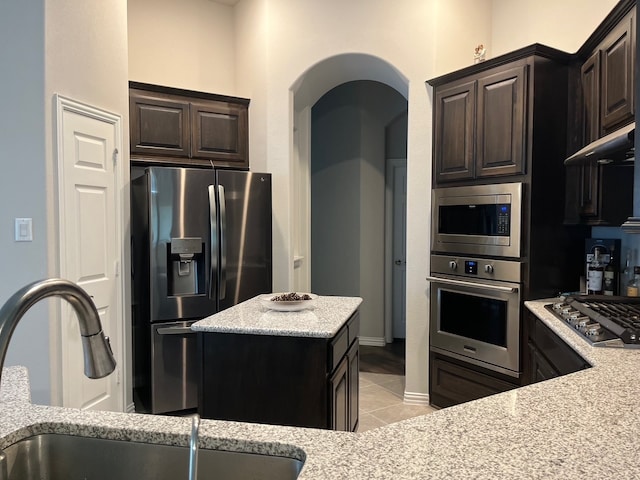 kitchen with dark brown cabinets, light stone countertops, sink, and appliances with stainless steel finishes