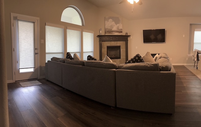 living room featuring ceiling fan, a fireplace, dark wood-type flooring, and lofted ceiling