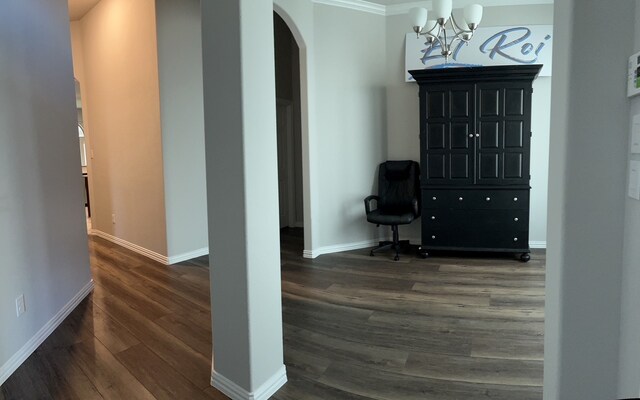 hall with dark hardwood / wood-style floors, crown molding, and a notable chandelier