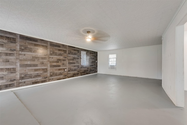 empty room featuring wooden walls, concrete flooring, and a textured ceiling