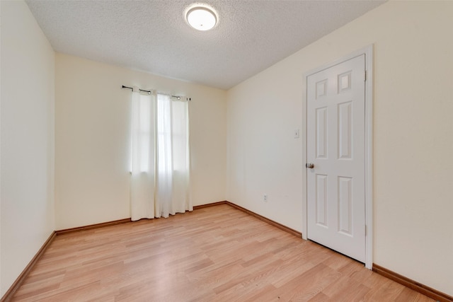 unfurnished room with a textured ceiling and light wood-type flooring