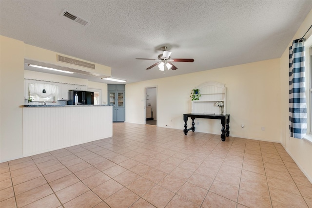 unfurnished living room with light tile patterned floors, a textured ceiling, and ceiling fan